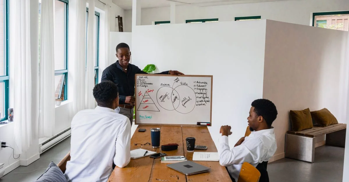 Trois hommes participent à une réunion d'affaires avec un tableau blanc dans un bureau moderne.