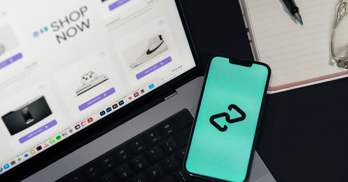 Un smartphone et un ordinateur portable affichant des plateformes d'achat en ligne, suggérant le commerce de détail numérique.