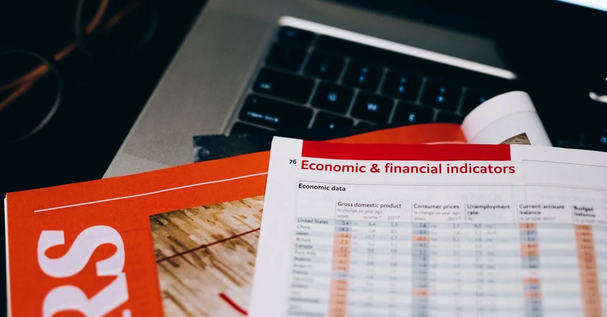 Gros plan détaillé de documents économiques et financiers sur un clavier d'ordinateur portable, mettant en avant l'analyse de données.