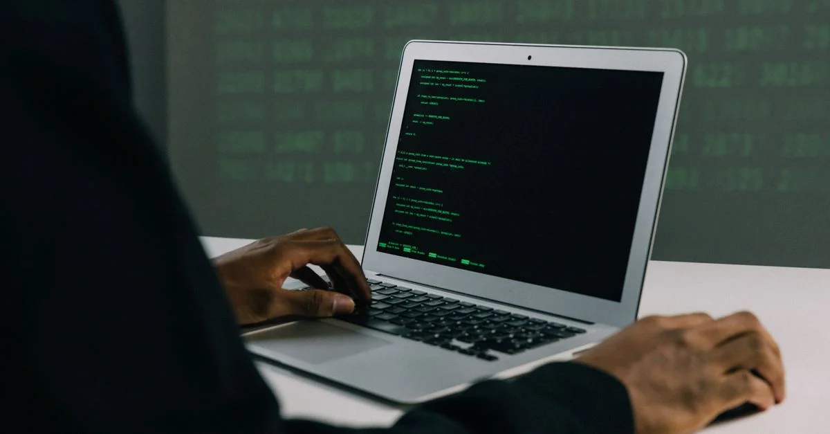 Un adulte concentré travaillant sur un ordinateur portable montre des compétences modernes en cybersécurité et en programmation à l'intérieur.