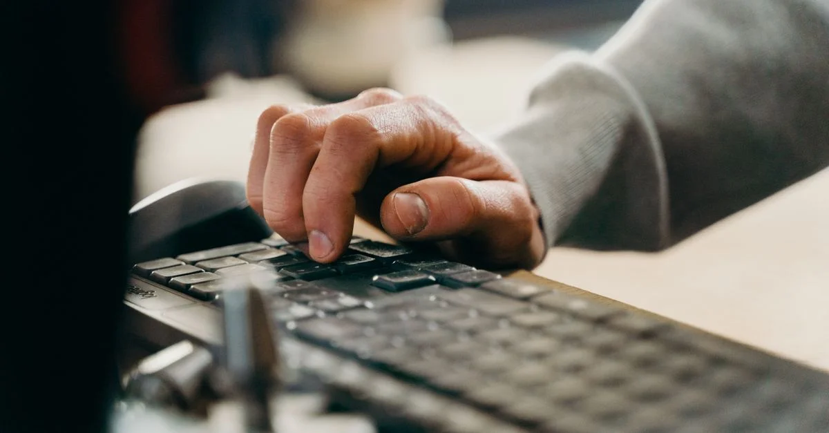 Plan rapproché d'une main tapant sur un clavier dans un bureau.