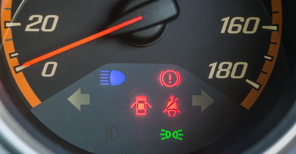 Vue détaillée d'un compteur de vitesse de voiture avec indicateurs d'avertissement illuminés.