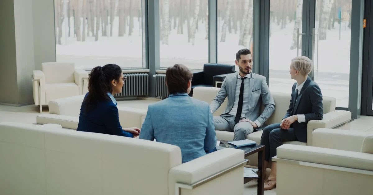 Groupe de professionnels en discussion dans un lounge de bureau lumineux.