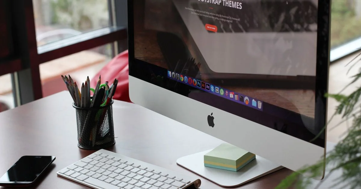 Un bureau propre et organisé avec un écran d'ordinateur, un clavier et des fournitures de bureau.