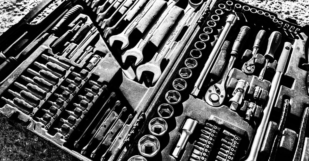 Photo en noir et blanc en gros plan d'un ensemble complet de claves et outils à douille dans une boîte à outils.